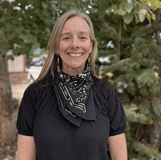 Samantha Bahn smiling outdoors in a black top and patterned bandana