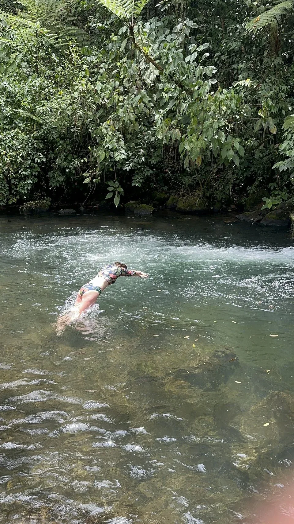 Guest diving into a clear jungle river pool in Costa Rica