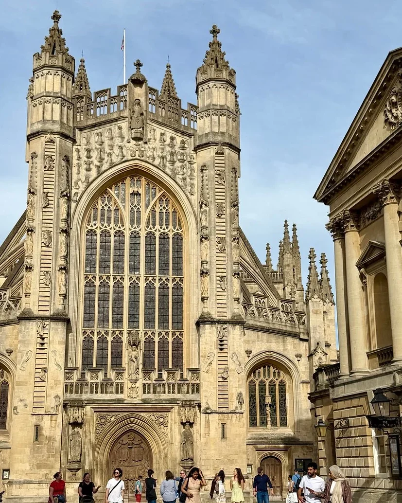 West front of Bath Abbey beside the entrance to the Roman Baths in Bath, England