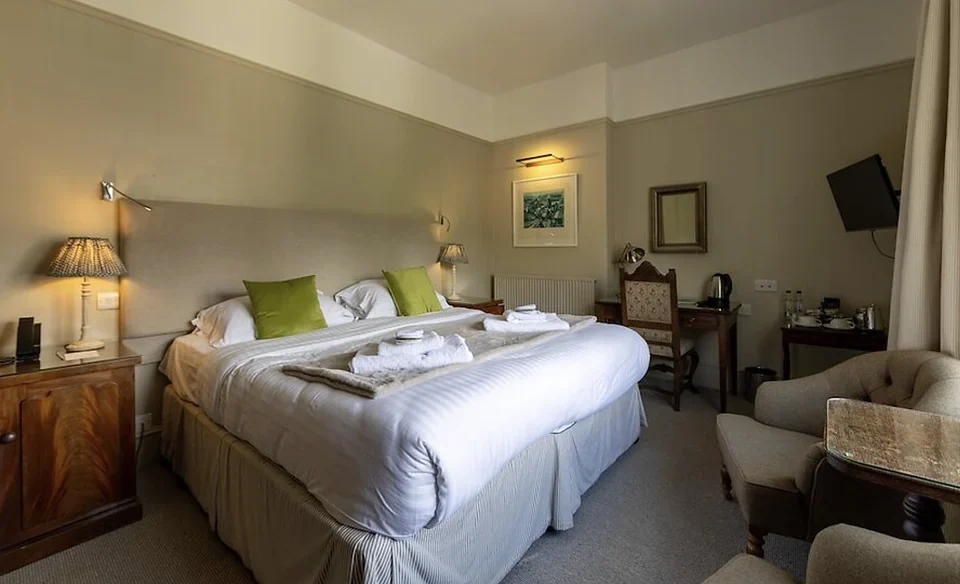 Deluxe hotel room with a king bed, green pillows, a writing desk, and armchairs