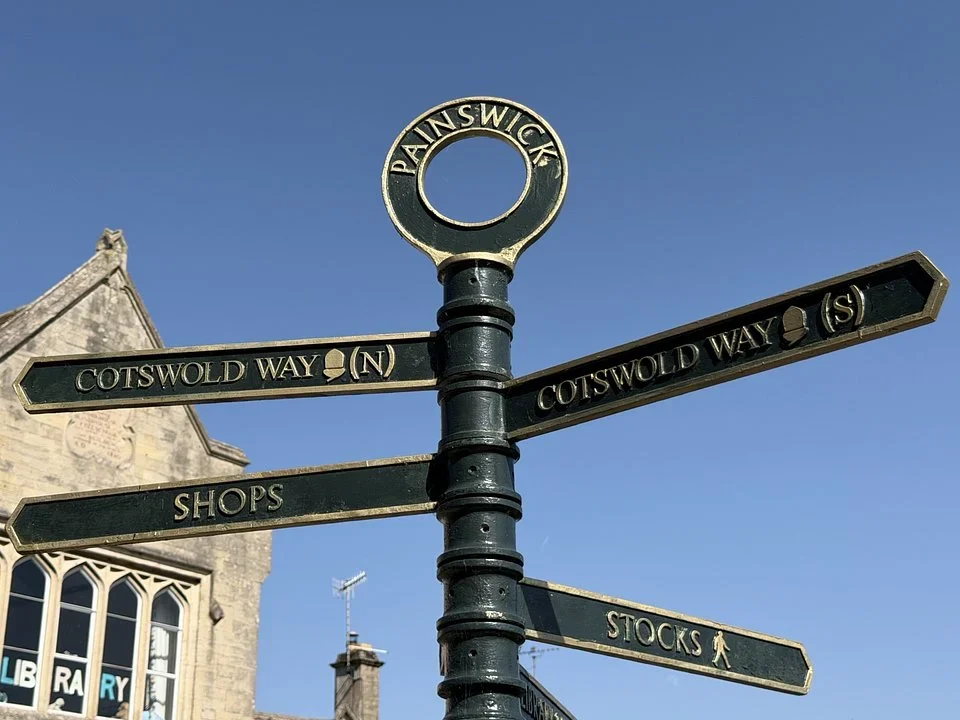 Green and gold Painswick signpost pointing to the Cotswold Way north and south