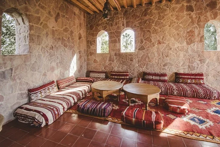 Stone lounge with floor cushions, Berber textiles, and low tables at the Morocco reading retreat