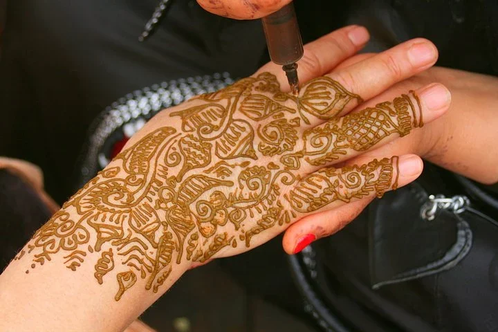 Intricate henna design being applied to the back of a hand