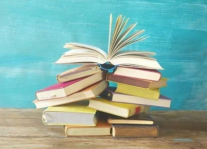 Stack of colorful hardcover books with one open on top