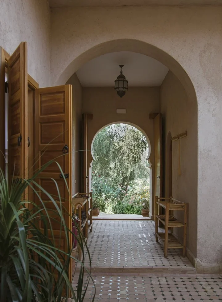 Tiled hallway with wooden doors leading through a keyhole arch to the garden