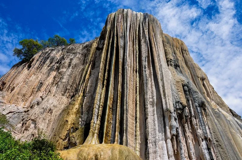The towering petrified waterfall at Hierve el Agua, streaked with mineral deposits against a blue sky