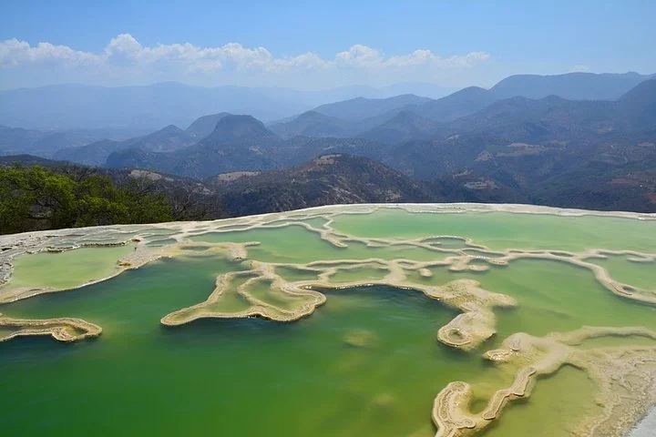 Green mineral pools at the edge of Hierve el Agua with layers of mountains stretching into the distance