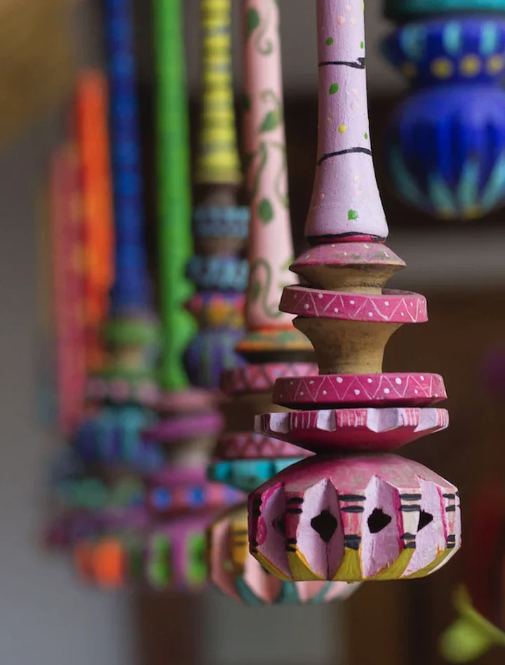 Row of hand-painted wooden crafts in pink, blue, and green hanging in a shop