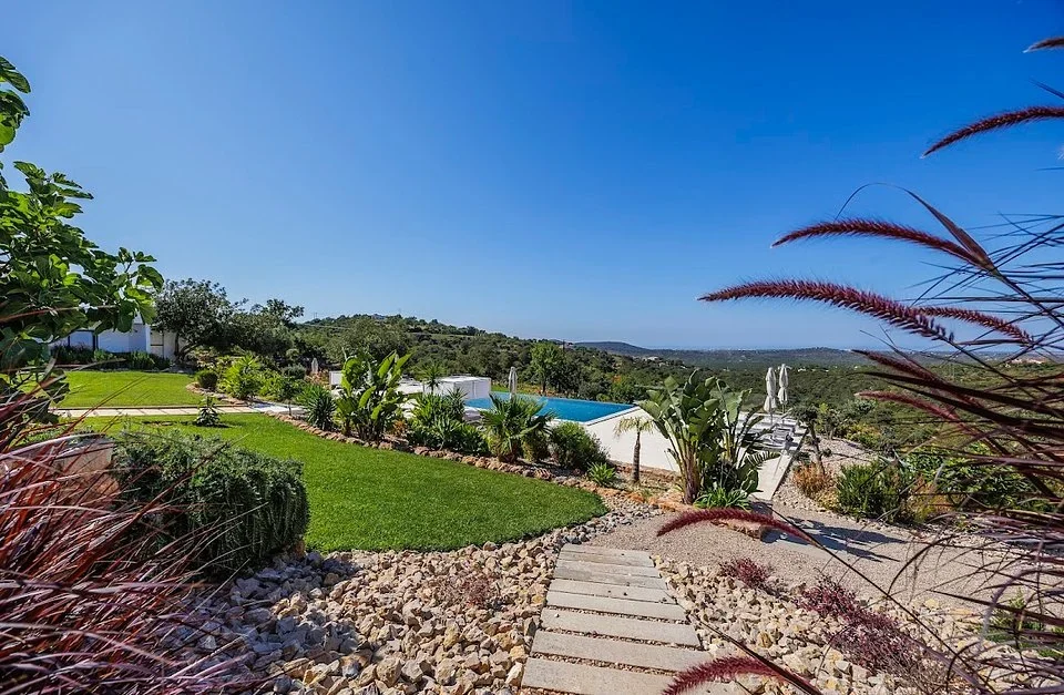 Stepping stone path through a lawn and garden leading to a pool with views over the hills