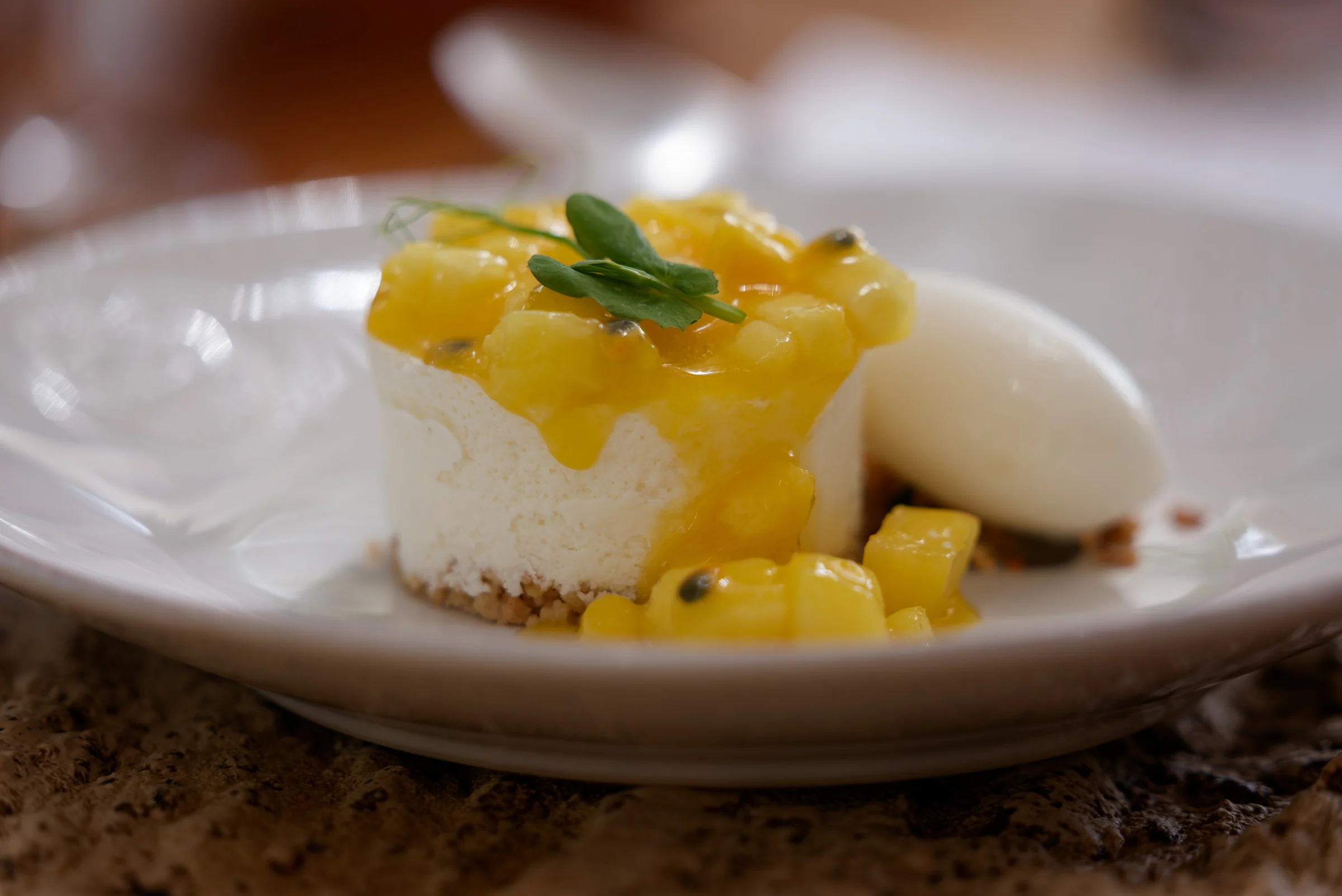 Cheesecake topped with mango and passion fruit beside a scoop of sorbet