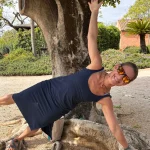 Guest holding a side plank under a tree at a Portugal retreat